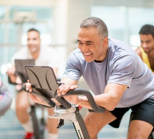An image showing a group of friends on stationary bikes at the gym